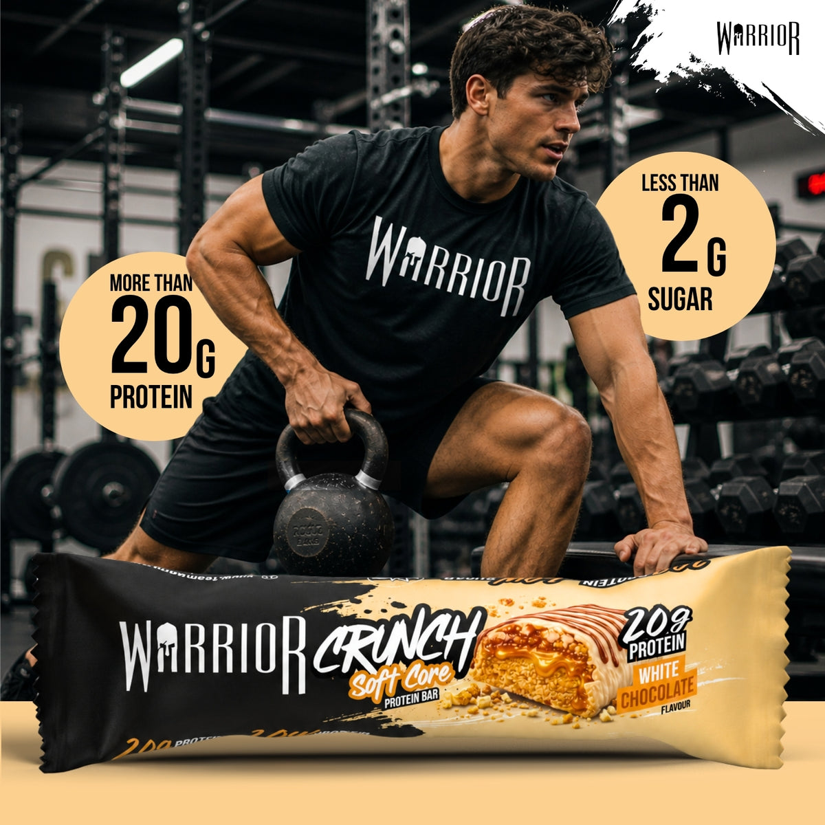 Warrior Crunch Soft Core White Chocolate protein bar wrapper on a gym floor, with a man in Warrior kit holding a kettlebell behind it and callouts for more than 20g protein and less than 2g sugar.